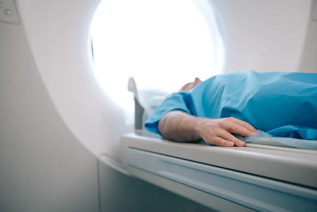 A patient lying in a hospital bed next to an MRI machine, preparing for a medical imaging procedure.